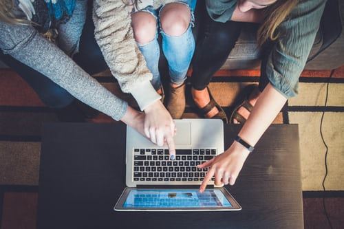 Three people pointing to laptop screen 